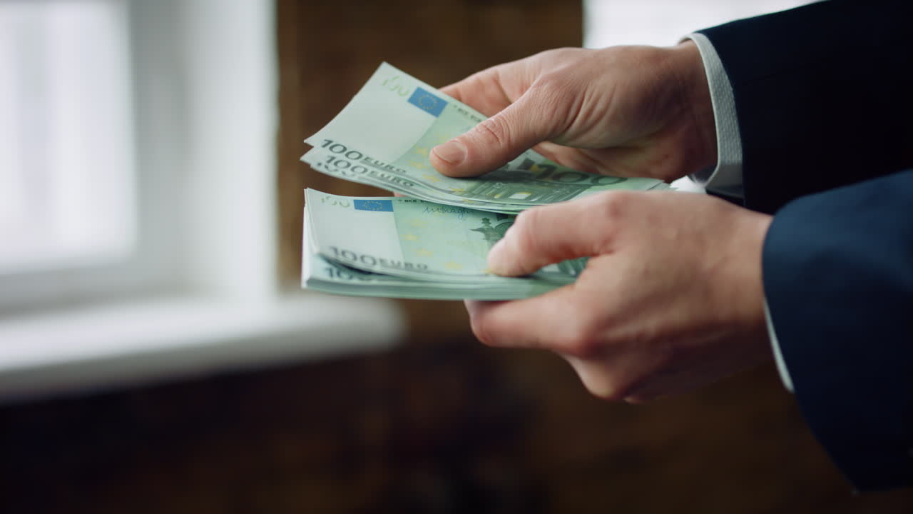 Mand tæller hundrede eurosedler, nærbillede. Mandehænder holder europæisk valuta.