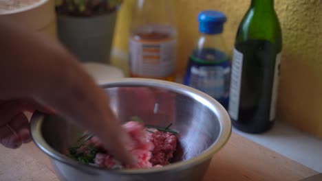 male hands mixing raw meat and other ingredients in stainless steel bowl, preparing japanese gyoza dumplings