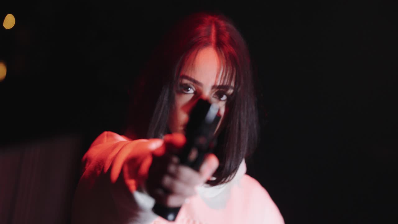 young beautiful woman aiming with gun at night