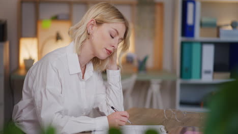 sad tired overworked woman working at desk in evening