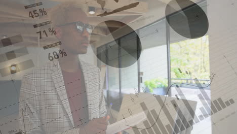 animation of financial data processing over african american businessman taking notes in office