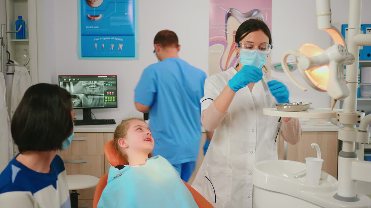 Stomatologist holding sterilized dental tools talking with little patient
