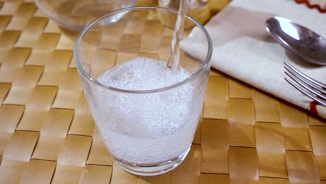 agua mineral vertiendo en un vaso, el desayuno de la mañana, cámara lenta con toma de seguimiento de rotación.