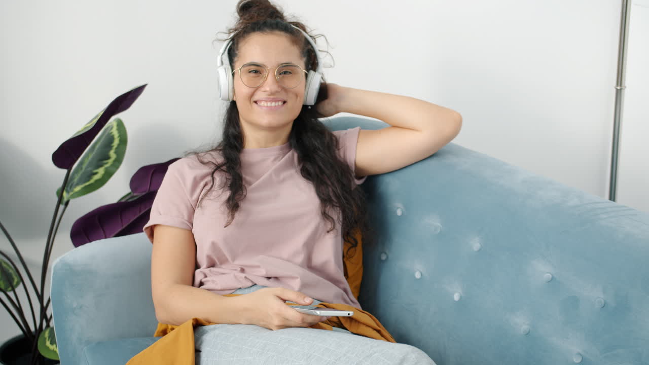 mujer relajándose en el sofá con auriculares