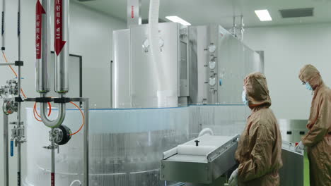 scientists working with modern equipment sterile pharmaceutical production cleanroom gleaming stainless steel, worker wearing protective uniform works industrial machinery advanced biopharmaceutical