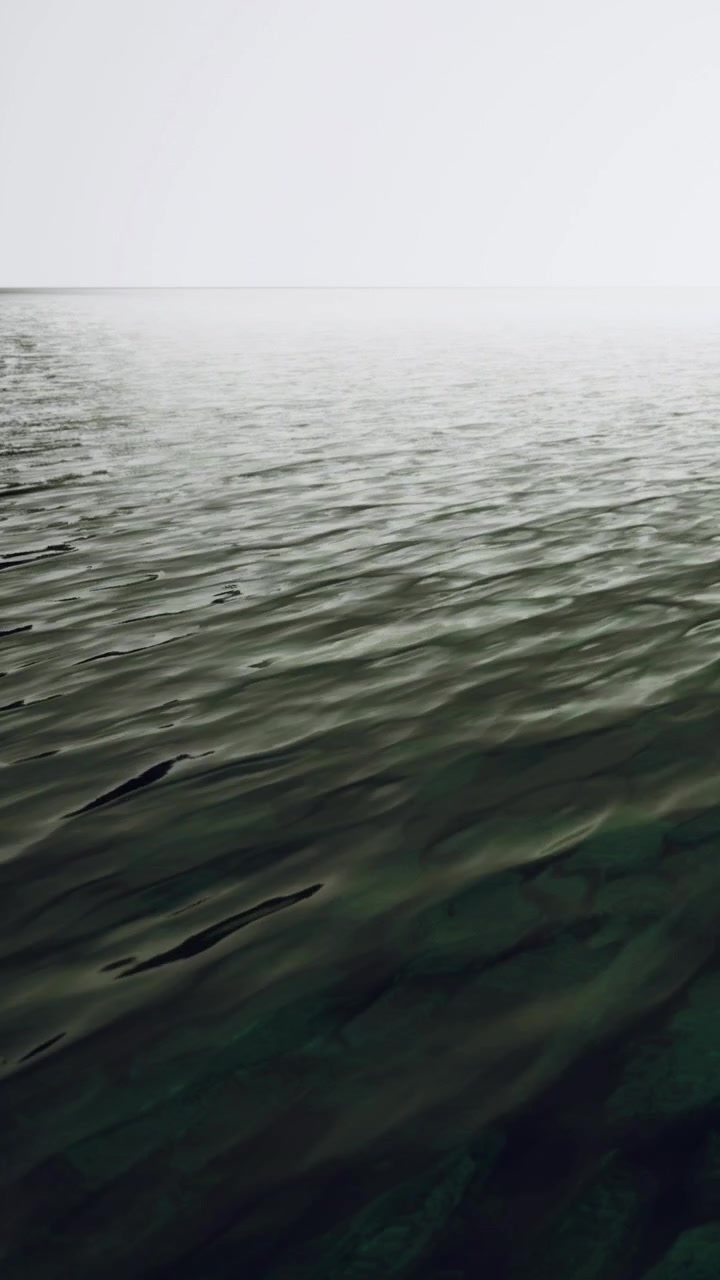 Rippling water surface under cloudy sky near a distant horizon at dusk
