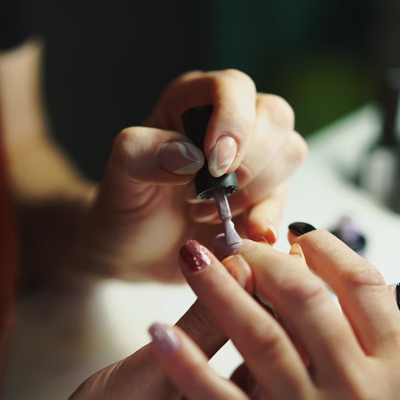master is making a manicure by gel-lacquer in black and pink colours for client in tha salon of beauty