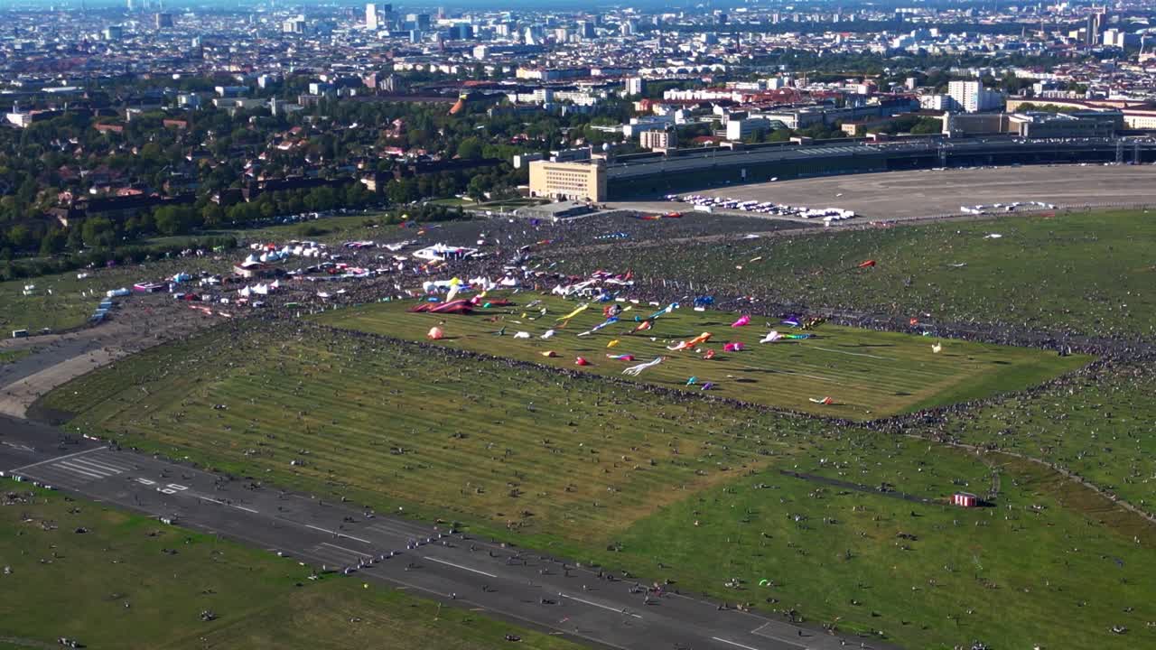 Large crowd of people gathering at the Tempelhofer Feld giant kite festival in Berlin, Germany. Fabulous aerial view flight descending drone