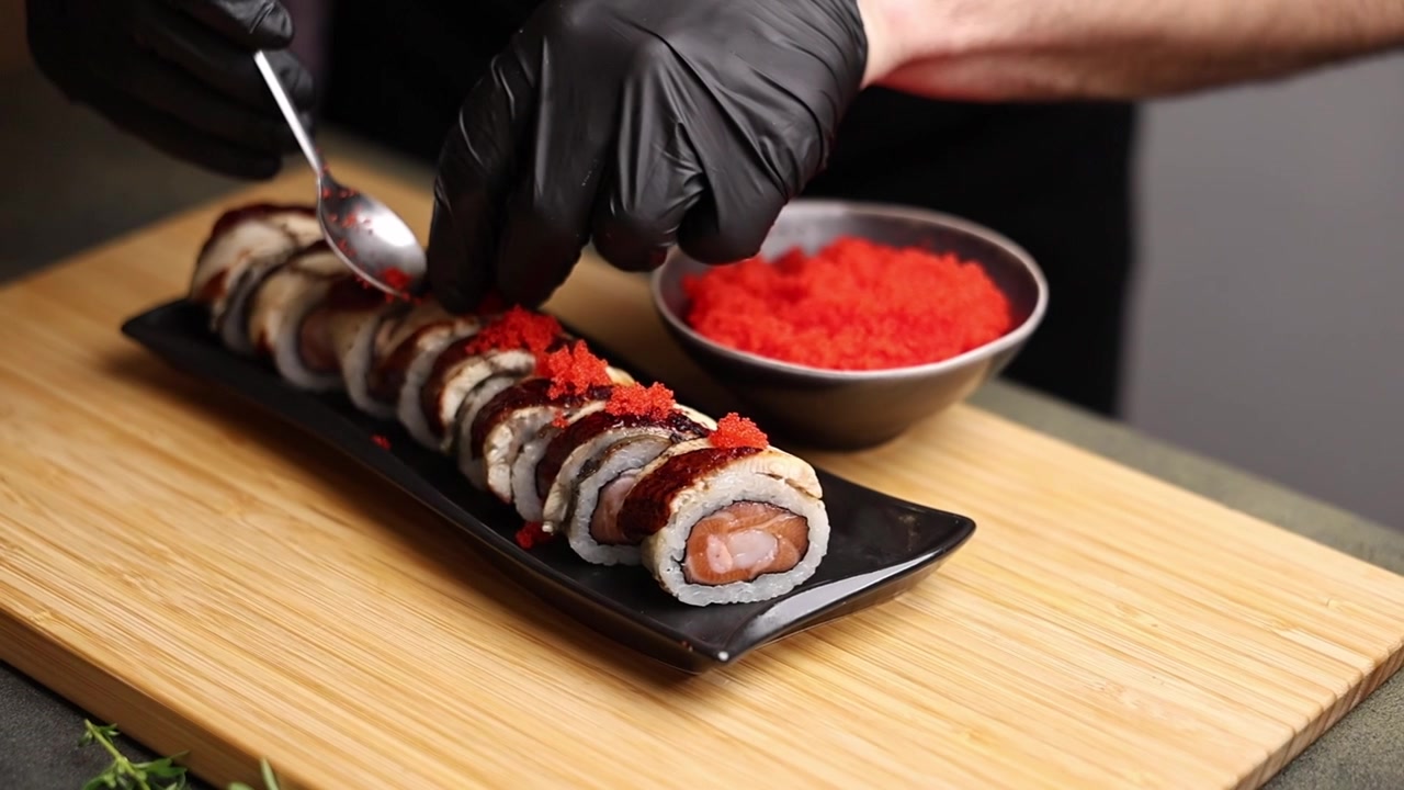 Chef professionista che guarnisce rotoli di sushi con tobiko rosso