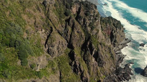 drone cerca de la formación de acantilados rocosos con la costa del océano paisaje marino revela playa solitaria agua azul y grandes olas choque
