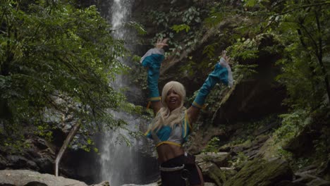 amazing fitness girl in an anime cosplayer costume enjoying nature at the base of an epic waterfall