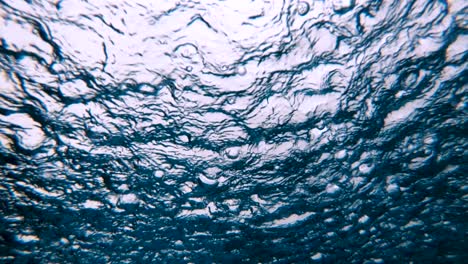 underwater view of heavy raining into the water surface, slow motion