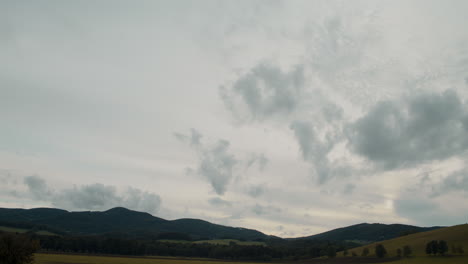 Meadow-against-mountains-under-cloudy-sky