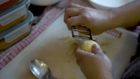 vista aérea de la mujer pelando patatas en la cocina junto a los contenedores de tupperware