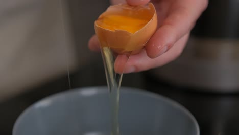 slow motion cracking an egg and using the shell to separate the yolk