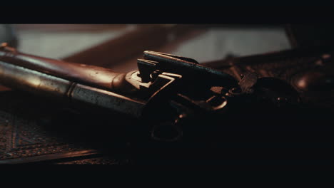 an old pistol on the table filled with old documents and maps inside the sailing ship cabin