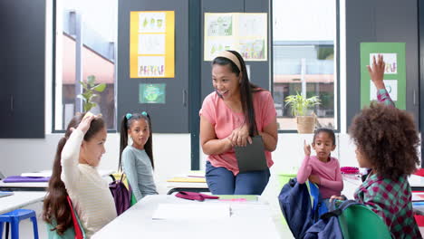 in school, teacher engaging with students raising hands in classroom discussion