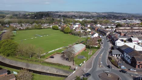 aerial drone shot panning over rural football pitch and housing estate, england