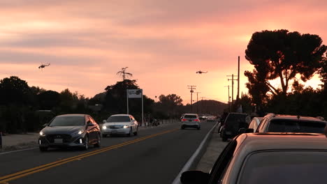 una puesta de sol naranja ardiente con helicópteros volando sobre el tráfico