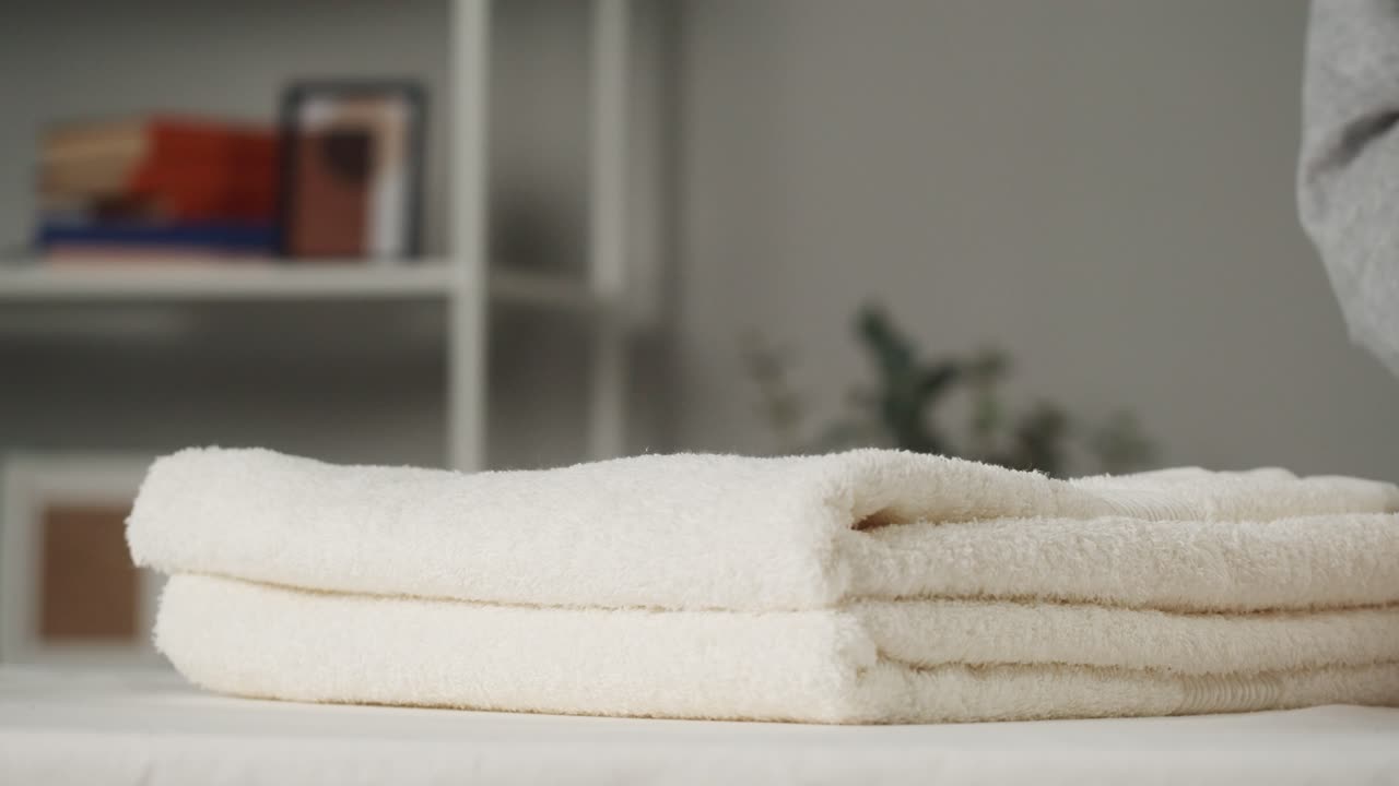 Kädet taittamassa ja pinoamassa puhtaita valkoisia pyyhkeitä
