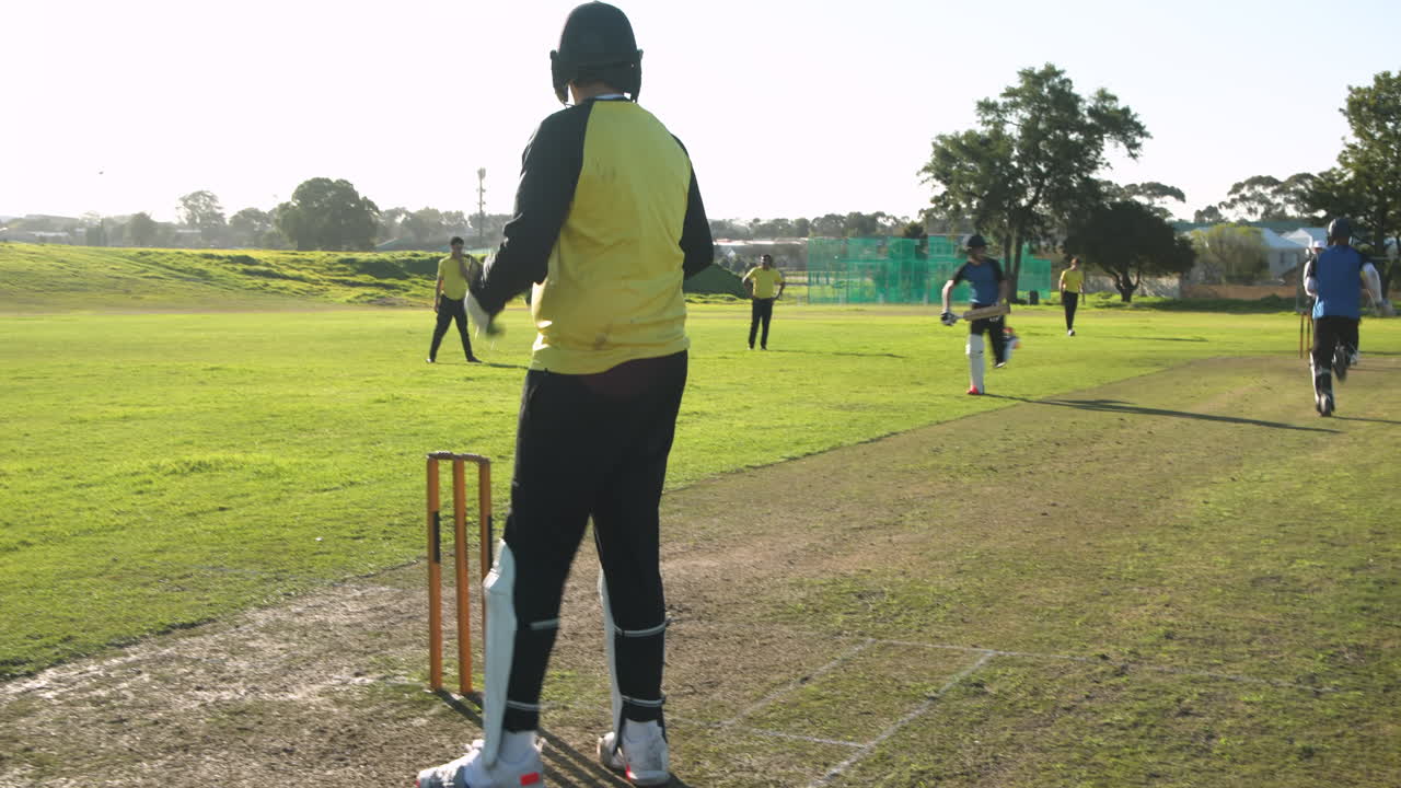 Cricket players running between wickets on sunny field during match