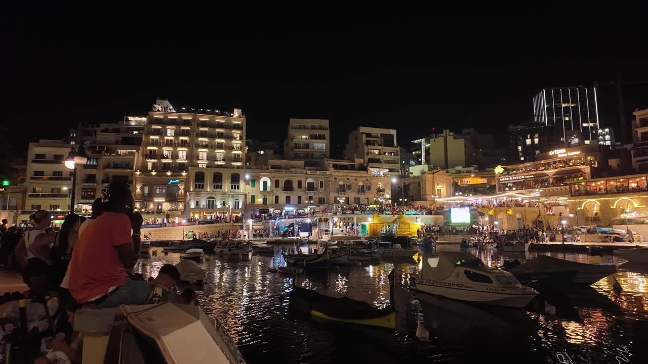 Lively Nighttime Harbor with Boats, Illuminated Buildings, and Crowds