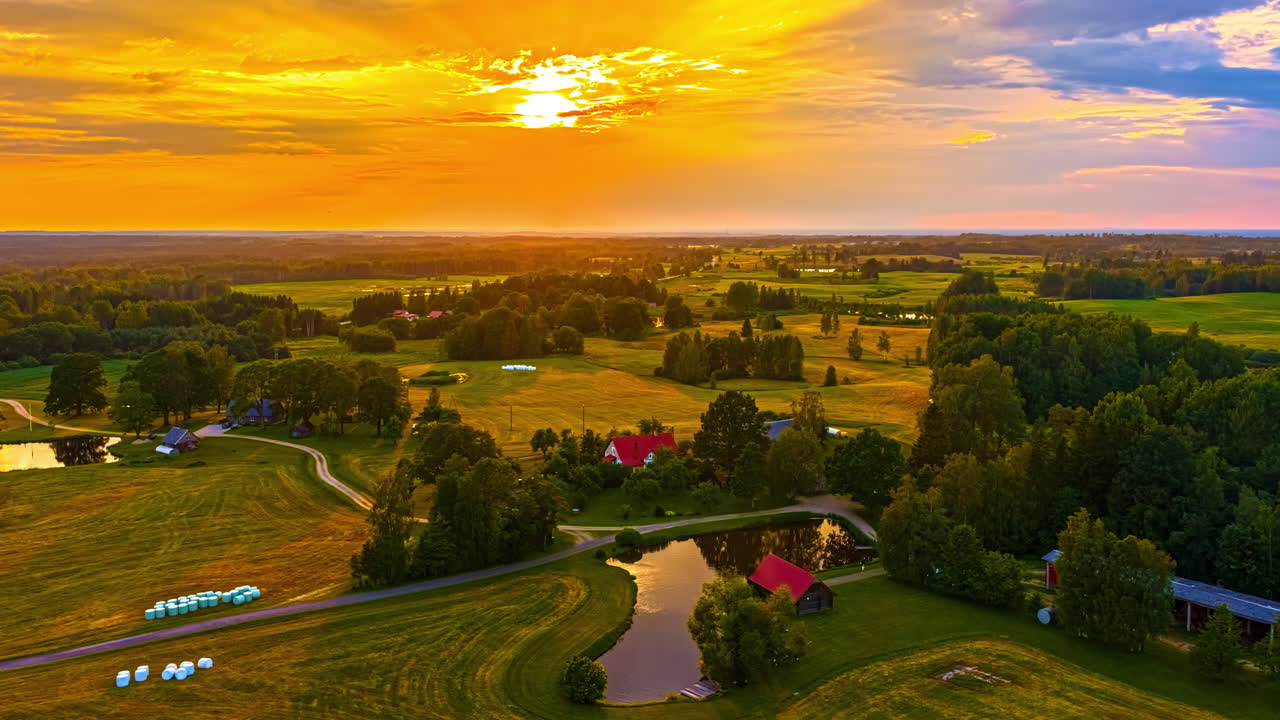 Setting sun casting light over rural farmland and fields reflecting in pond, golden to blue hour dusk passage of time
