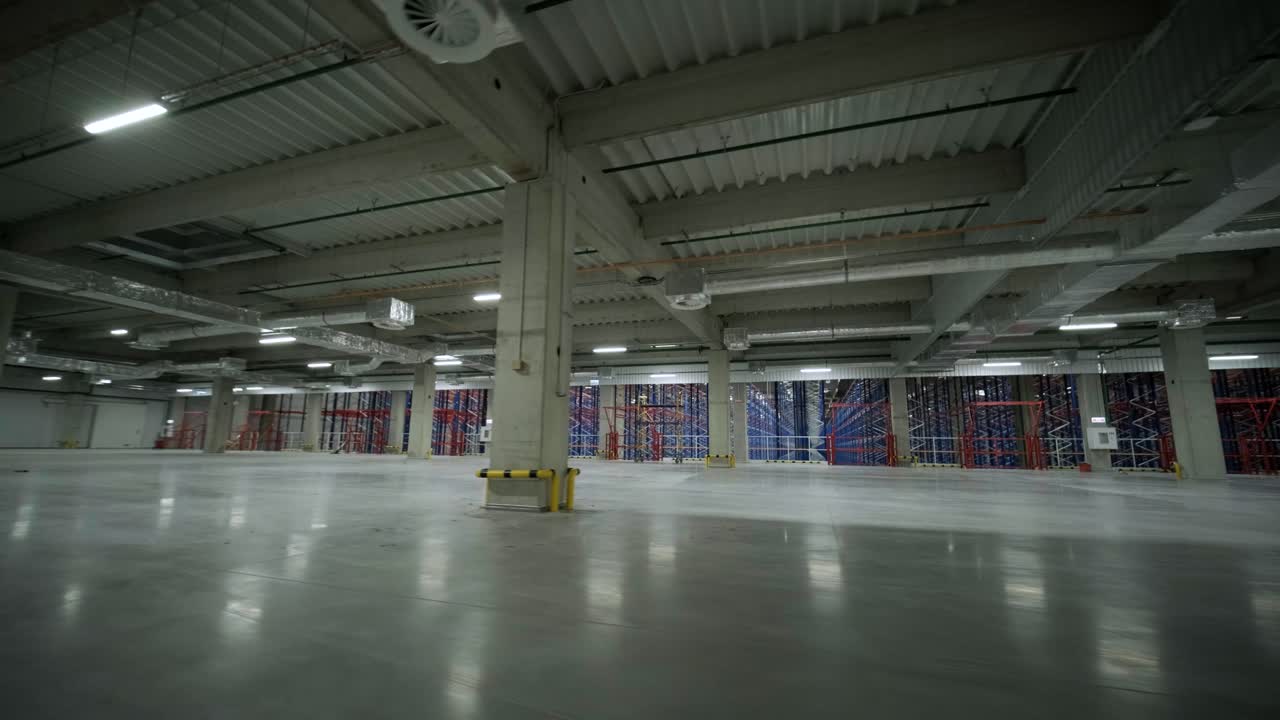 Stort og moderne lager under opførelse, med metalreoler og andet industrielt udstyr.
