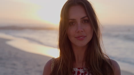 portrait of happy young woman turns head smiling enjoying summer vacation running hand through hair on beach sunset slow motion