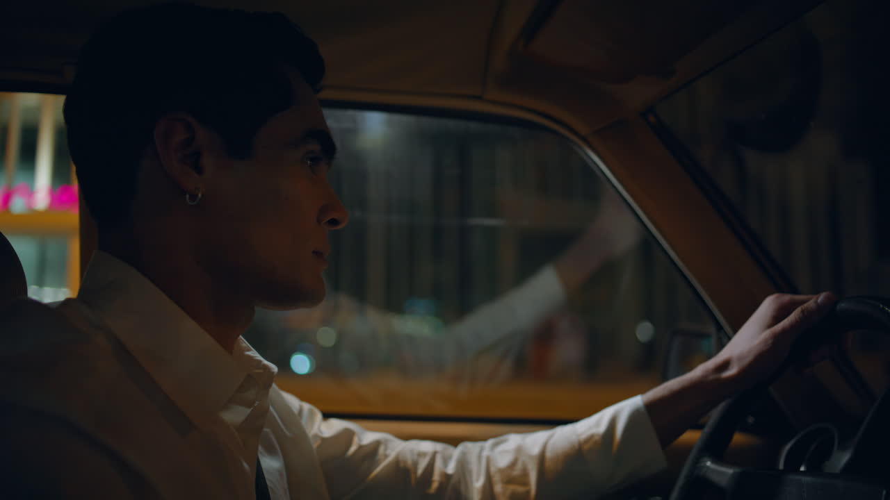 밤에 도로를 운전하는 자신감 있는 남자. 운전자가 스티어링 을 들고 있다.