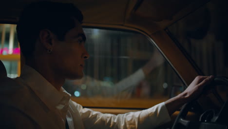 confident man driving road at night city close up. driver holding steering wheel