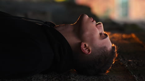 vertical shot of urban modern young guy leaning head against the wall in a reflective manner