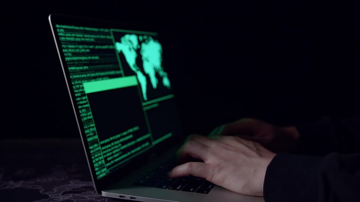Hackerens hænder bruger bærbar computer til at hacke i et mørkt rum