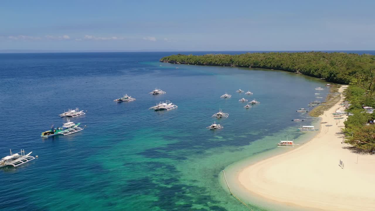 Boats in the harbor. Stunning turquoise water and white sand beach. Flying backwards. Philippines, Asia