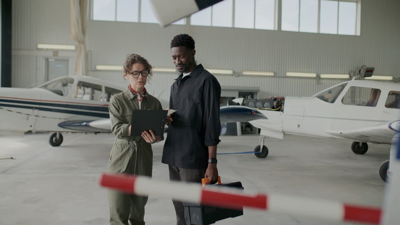 Mechanic Listening to Instructions from Female Aircraft Engineer in Hangar