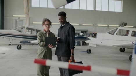 mechanic listening to instructions from female aircraft engineer in hangar