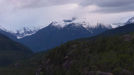 british columbia mountains, green trees and a cloudy sky.