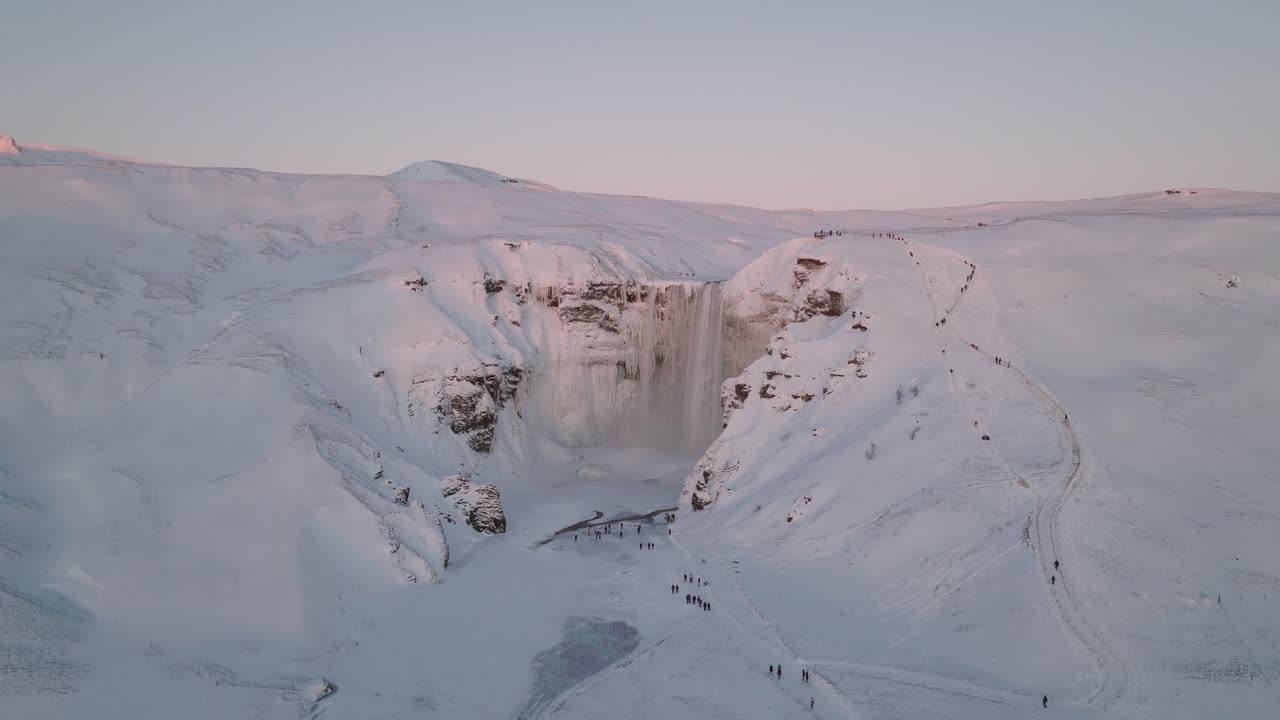 vista panorámica aérea de un paisaje invernal cubierto de nieve, de la cascada de skogafoss, en islandia, al atardecer