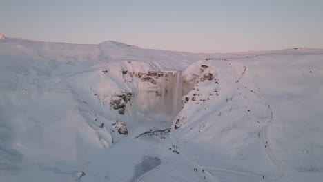 aerial panoramic view of a winter landscape covered in snow, of skogafoss waterfall, in iceland, at sunset