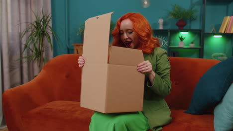 Happy-redhead-woman-shopper-unpacking-cardboard-box-delivery-parcel-online-shopping-purchase-at-home