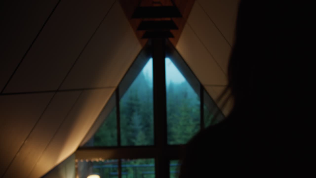 silueta de una chica que mira por la ventana en el bosque verde en las montañas. noche romántica, chica mirando por la ventana