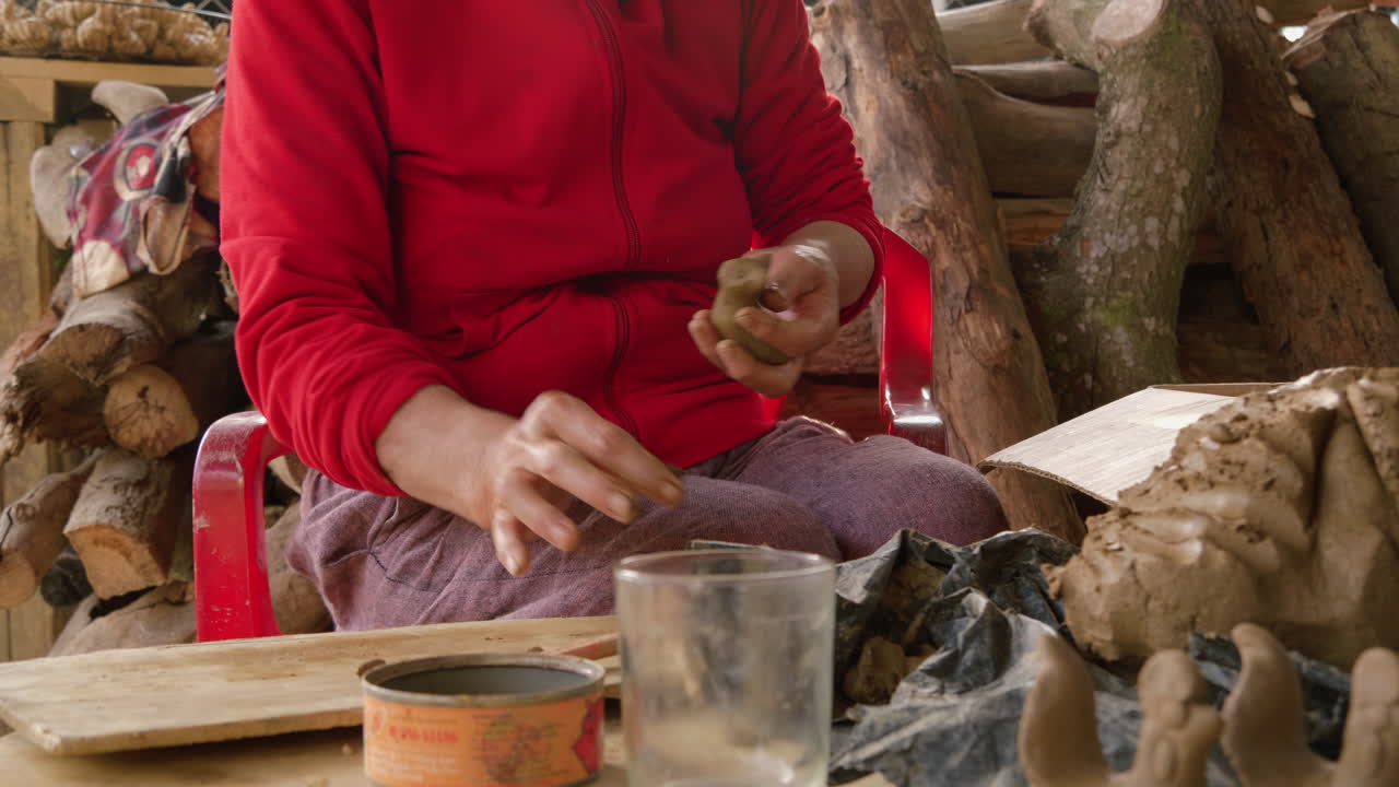 una mujer asiática elabora pequeñas figuras de animales en arcilla para flautas con forma de animales de recuerdo en thanh ha, capturando el arte del turismo