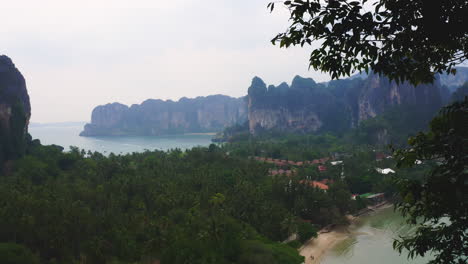 View-through-tree-branches-to-village-in-Railay-beach-bay,-Thailand