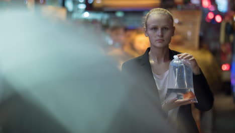timelapse de una mujer con peces en una bolsa de plástico entre la multitud