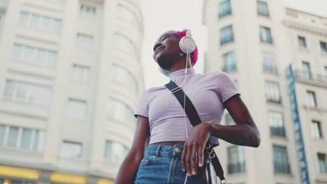 young person with pink hair dancing to music in the city