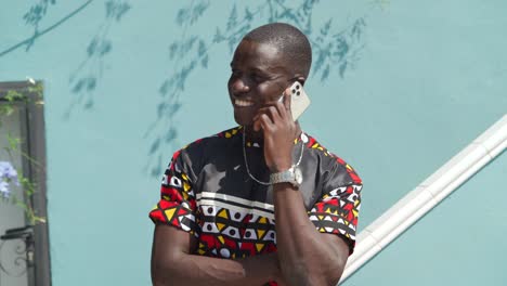 Black-man-having-phone-call-near-wall