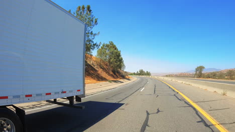 passing a long-haul freightliner semi truck as it ascends a steep grade on the highway - slow motion