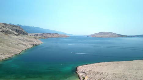 An-aerial-footage-over-beautiful-beach,-green-and-blue-waters-of-Adriatic,-stunning-barren-landscape-on-island-Pag,-Croatia-in-summer