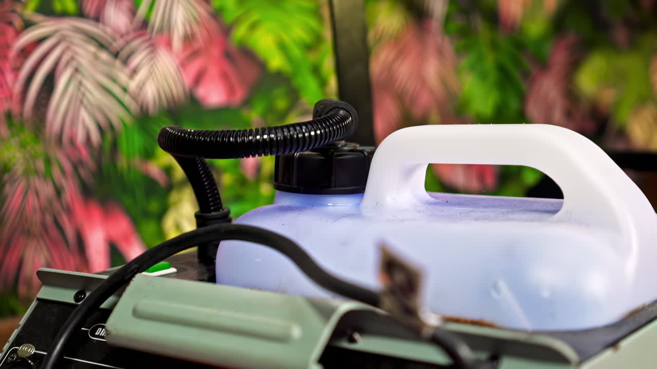 Professional smoke machine on a movie set with colorful background of palm leaves. Close up of the stuff in a pavilion