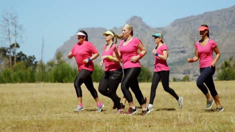 Entrenadora-Ayudando-A-Mujeres-Corriendo-En-El-Campo-De-Entrenamiento